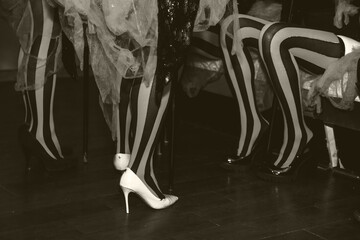 Close up of circus performers women legs in striped red-black stockings in dressing room, black...