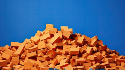 About 500 terra cotta bricks randomly piled on yellow surface, blue background
