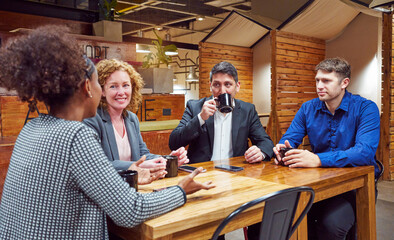 portrait four businesspeople colleagues sitting indoors drinking coffee talking	