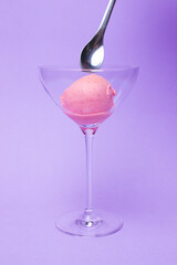 A scoop of ice cream in a beautiful glass bowl on a colored background.