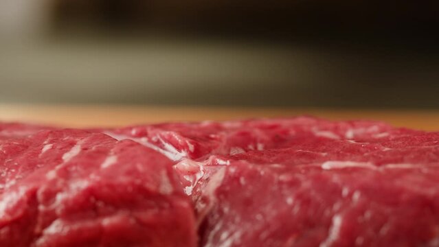 Meat on wooden desk close-up macro.Man chef cooking beef steak angus. Professional cheif preparing meat in restaurant kitchen. Delicious barbecue pork, spicy cuisine, american barbeque. 