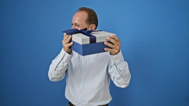 Confident middle age man, full of joy, hugging his surprise birthday present, smiling cheerfully. isolated on a white wall, expressing happiness and positivity.