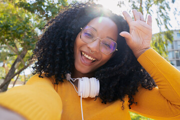 Beautiful woman with curly hair glasses smiling taking a photo of herself