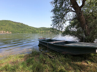 Beautiful landskape of the boat on the lake. Green forest  and fields. Sunny day in nature.