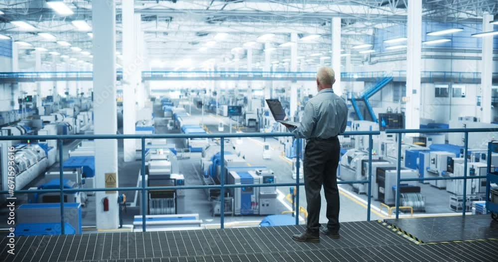 Poster Senior Factory Manager Working on Laptop at a Futuristic Industrial Manufacture with Autonomous AI Robots. Specialist Monitoring All the Data on a Computer, Checking Reports and Planning Workload