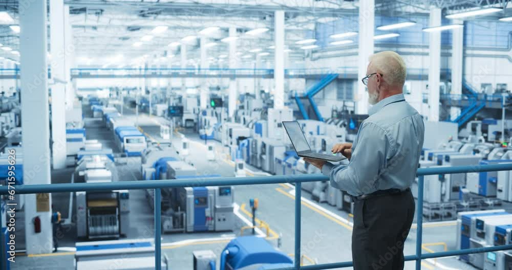 Poster Middle Aged Male Engineer Standing on a Platform, Using Laptop Computer and Monitoring Production at a Modern Automated Electronics Manufacture with AI Robots. Factory Technician at Work