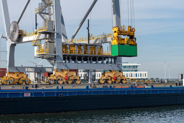 Large gantry cranes moving containers in ‘ship to shore’ logistics  into container river barge...