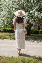 An attractive long-haired woman walks in the spring in the park of blooming apple trees.