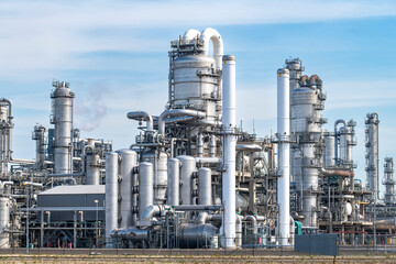 Part of a chemical plant or refinery with fractioning or distillation towers, boilers and pipes for oil and chemicals against a blue sky - obrazy, fototapety, plakaty