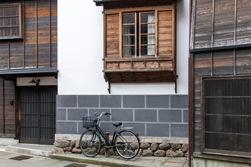 Fototapeta na wymiar Urban street view of façade of typical Japanese house with modern stone and traditional wooden window and door features and bicycle parked in front of building