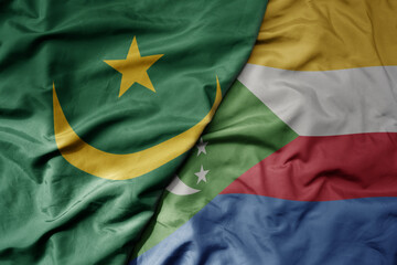 big waving national colorful flag of mauritania and national flag of comoros .