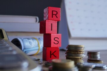 Wooden cubes with text RISK surrounded by calculator and money. Risk in business, financial and...