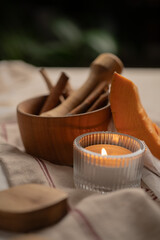 Wooden mortar or pounder with cinnamon sticks and anise on table with pumpkin and candle.