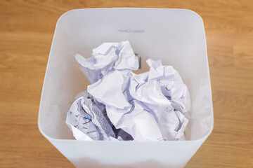 Top view and closed up shot of crumple paper waste on a wooden floor, symbolizing management's approach to discard, rejection, mistake, and creative failures including recycling and reuse concept.