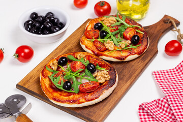 Two pizzas with mozzarella cheese, nuts, arugula, tomatoes and olives. Italian food. Vegetarian food.