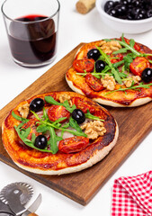 Two pizzas with mozzarella cheese, nuts, arugula, tomatoes and olives. Italian food. Vegetarian food.