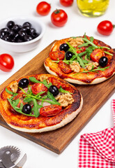 Two pizzas with mozzarella cheese, nuts, arugula, tomatoes and olives. Italian food. Vegetarian food.