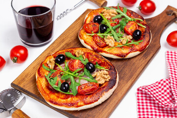 Two pizzas with mozzarella cheese, nuts, arugula, tomatoes and olives. Italian food. Vegetarian food.