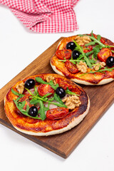 Two pizzas with mozzarella cheese, nuts, arugula, tomatoes and olives. Italian food. Vegetarian food.