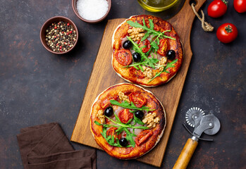 Two pizzas with mozzarella cheese, nuts, arugula, tomatoes and olives. Italian food. Vegetarian...