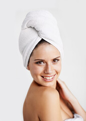 Happy, beauty and woman with towel in a studio for health, wellness and natural face routine. Smile, skincare and portrait of young female model with facial dermatology treatment by gray background.