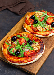 Two pizzas with mozzarella cheese, nuts, arugula, tomatoes and olives. Italian food. Vegetarian food.
