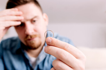 Distressed Man Holding Wedding Ring, Symbolizing Relationship Trouble or Separation