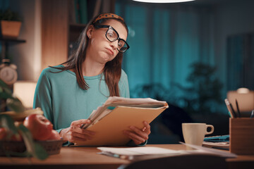 Frustrated woman checking paperwork at home - obrazy, fototapety, plakaty