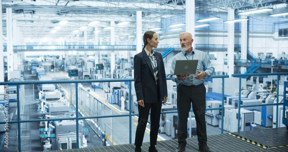 Aufkleber Male Engineer and Female Project Manager Standing on a Platform, Talking, Using Laptop Computer and Monitoring Production at a Modern Automated Electronics Manufacture with AI Robotic Arms