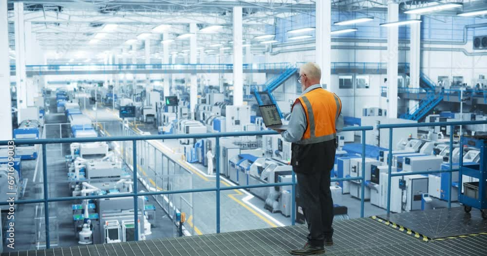 Leinwandbilder experienced male engineer standing on a platform, wearing a high-visibility vest, using laptop compu