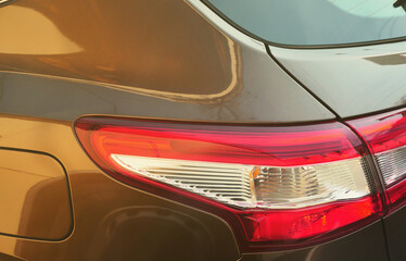 Red taillight of a brown passenger car close-up. Detailed photo of one of the car parts