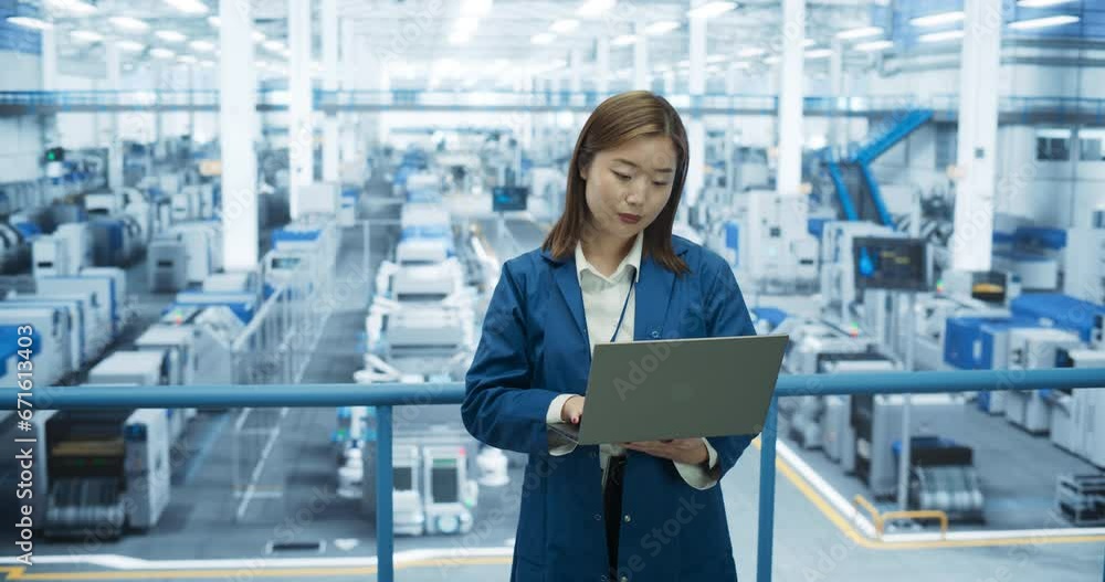 Aufkleber young asian female engineer standing at a factory, using laptop computer at an electronics manufactu