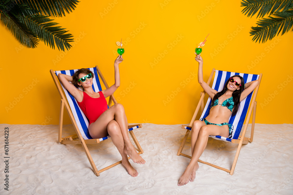 Wall mural Photo of two girls rest summer resort raise glass toast for perfect relax isolated over vivid color background