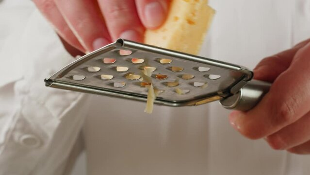 Italian cheese grater closeup, Close up of grated cheese, grating for pasta or pizza. Parmesan or gouda cooking by chef in cafe.