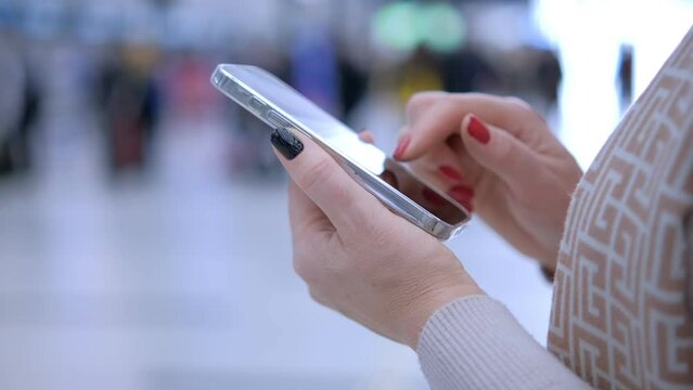 Close-up. People in international airport. Female traveler look at phone, search for boarding pass or flight cancelation information. 4K
