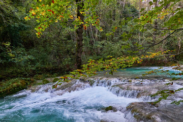 The waterfalls and crystal clear, blue, turquoise and green waters of the Nacedero del Urederra, with its beech forest with its autumn colors in the Sierra de Urbasa-Andía. Navarre. Spain