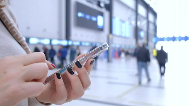 Close-up. People in international airport. Female traveler look at phone, search for boarding pass or flight cancelation information. 4K