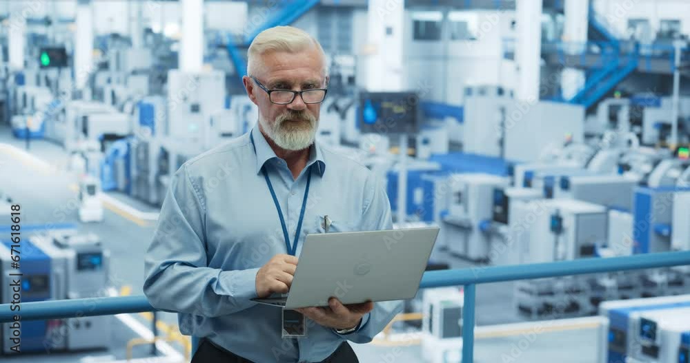 Poster Portrait of an Adult Engineer Standing on a Platform, Using Laptop Computer at an Electronics Factory. Technician Making Technical Upgrades Online Over an Internet Software