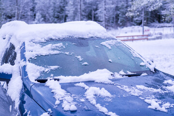 Fototapeta na wymiar automobile windshield cleaned of freshly fallen snow on a winter morning with forest in the background room for text