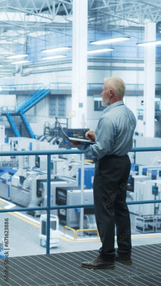 Poster Vertical Screen: Male Engineer Standing on a Platform, Using Laptop Computer and Overlooking Production at a Modern Automated Electronics Manufacture with AI Support. Factory Executive at Work