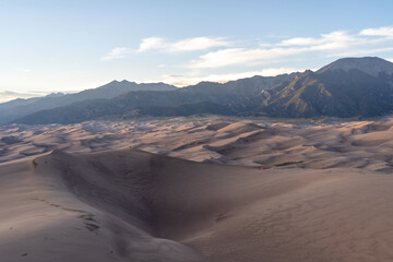 Fototapeta na wymiar View from the top at golden hour and sunset at Great Sand Dunes National Park in Colorado on a sunny summer evening, with mountains in the background
