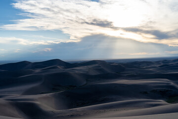 View from the top at golden hour and sunset at Great Sand Dunes National Park in Colorado on a sunny summer evening, with mountains in the background