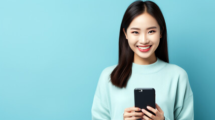 Fototapeta premium Young woman smiling happy pretty and holding mobile phone. Typing message doing ecommerce shopping on cell, using trendy apps on cellphone isolated on blue background with copy space.