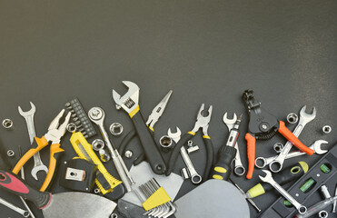 Handyman tool kit on black wooden table. Many wrenches and screwdrivers, pilers and other tools for...