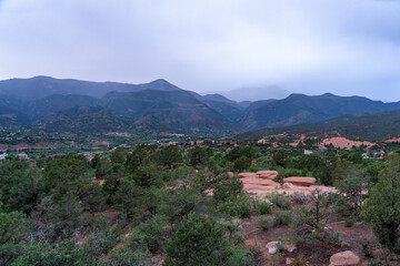 Fototapeta na wymiar A view of a rainstorm over Pike's Peak and other blue misty mountains on a cloudy summer evening, as viewed from Garden of the Gods in Colorado Springs, CO