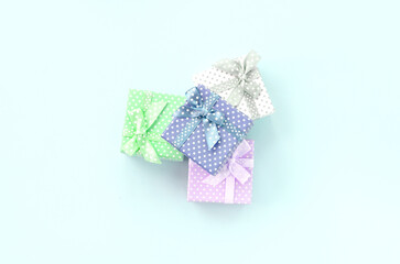 Pile of a small colored gift boxes with ribbons lies on a violet background. Minimalism flat lay top view.