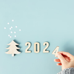 Close up image of hand folds wooden numbers into the number of the new year 2024