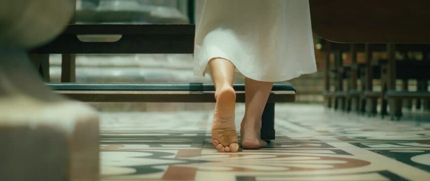 Barefoot pilgrim tramp woman praying in cathedral church. Confession of sins to a priest. Girl came to the priest to repent.