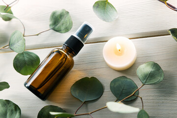 blank perfume spray bottle with eucalyptus leaves and candle on white wooden table
