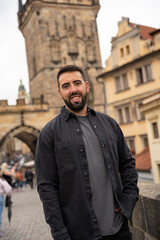 Young male tourist with beard posing on the Charles Bridge, Prague.